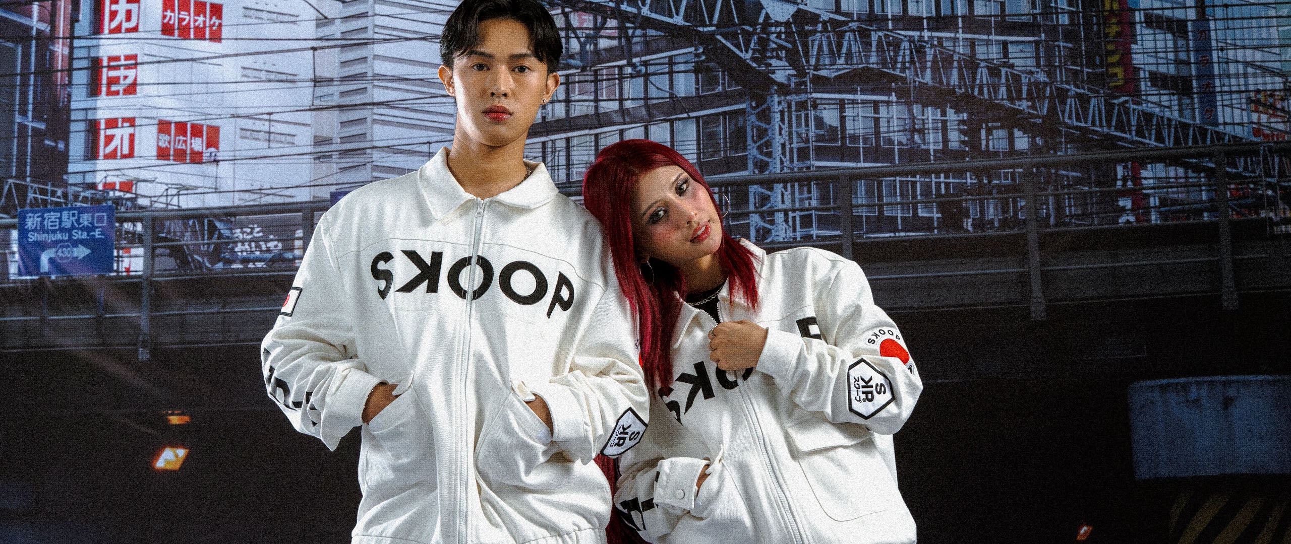 Two people wearing white jackets with logos in an urban setting